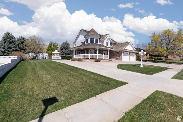 889 Upland Dr, Richfield, UT 84701 - victorian-style house featuring driveway, a gazebo, a front lawn, a porch, and brick siding