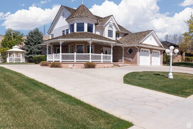 889 Upland Dr, Richfield, UT 84701 - victorian-style house featuring a front yard, covered porch, brick siding, a gazebo, and an attached garage