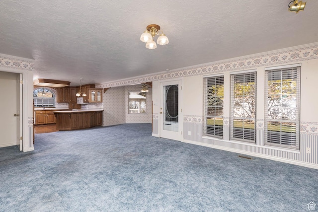 889 Upland Dr, Richfield, UT 84701 - unfurnished living room with a textured ceiling, wallpapered walls, dark carpet, and a wealth of natural light
