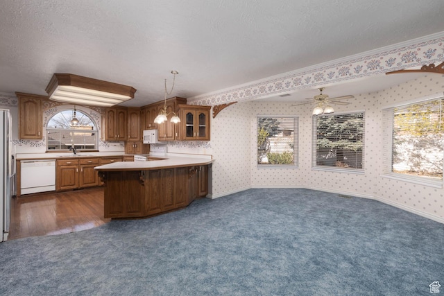 889 Upland Dr, Richfield, UT 84701 - kitchen with white appliances, wallpapered walls, brown cabinets, a sink, and dark carpet