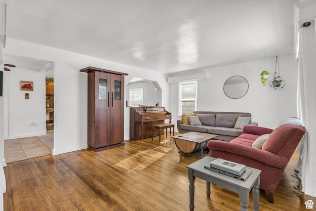 living area featuring baseboards, wood finished floors, and arched walkways
