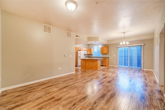 170 W Albion Village Way Unit 202, Sandy, UT 84070 - unfurnished living room with a textured ceiling, a chandelier, light wood-type flooring, and baseboards