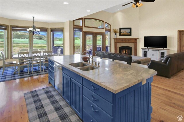 667 Hardscrabble Ct, Porterville, UT 84050 - kitchen featuring stainless steel dishwasher, a sink, blue cabinets, open floor plan, and light wood finished floors