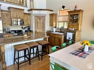 620 W Cisco Run Run, Garden City, UT 84028 - kitchen with stainless steel microwave, a breakfast bar area, brown cabinetry, range, and light wood-type flooring
