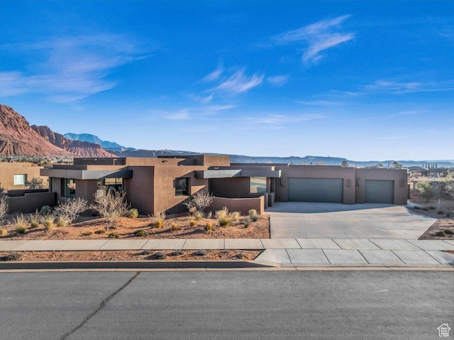 533 S Kwavasa Dr, Ivins, UT 84738 - view of front facade featuring stucco siding, concrete driveway, a mountain view, and a garage
