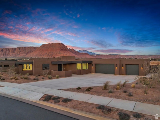 adobe home with a mountain view, stucco siding, driveway, and an attached garage