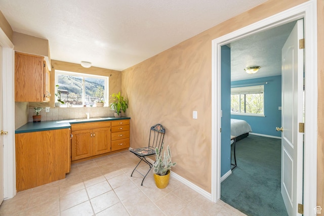 1910 E Canyon Ridge Dr, North Logan, UT 84341 - kitchen featuring decorative backsplash, a sink, baseboards, light tile patterned flooring, and brown cabinetry