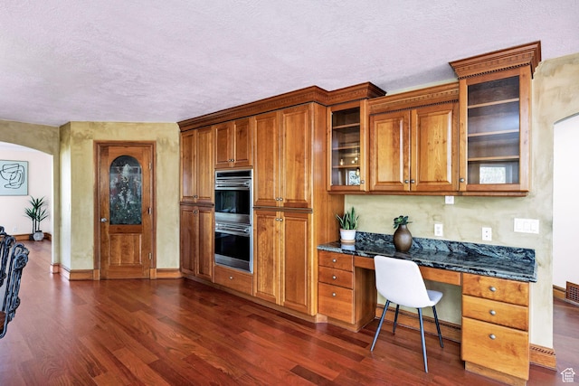 1910 E Canyon Ridge Dr, North Logan, UT 84341 - kitchen with stainless steel double oven, brown cabinetry, dark wood-type flooring, built in study area, and a textured ceiling