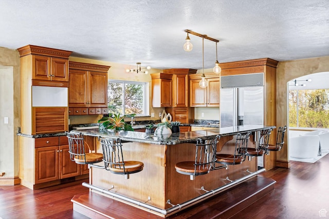 1910 E Canyon Ridge Dr, North Logan, UT 84341 - kitchen with a center island, a textured ceiling, dark wood-style flooring, and a kitchen bar