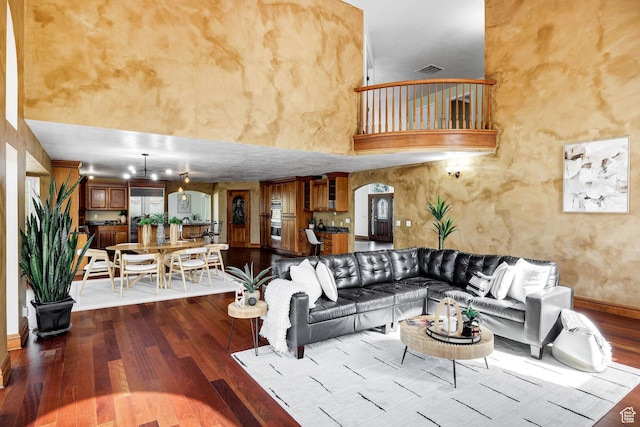 1910 E Canyon Ridge Dr, North Logan, UT 84341 - living room featuring dark wood finished floors, arched walkways, baseboards, visible vents, and a towering ceiling