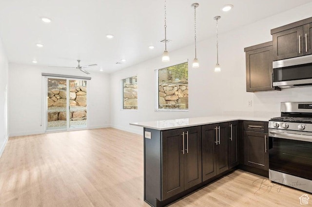 kitchen with appliances with stainless steel finishes, light wood-style floors, ceiling fan, and light countertops