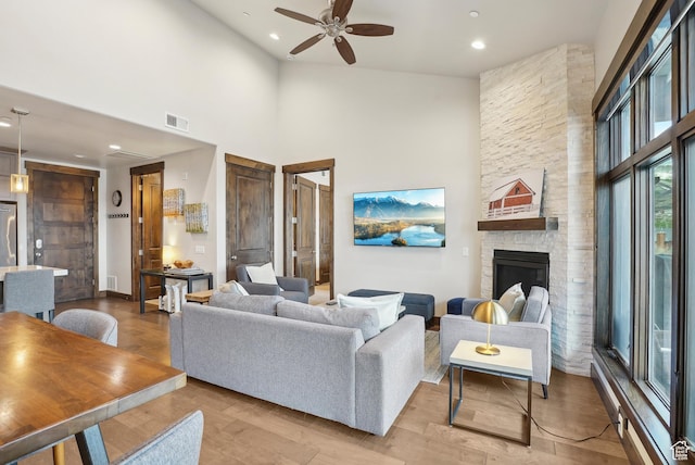 living area with visible vents, wood finished floors, ceiling fan, and a towering ceiling