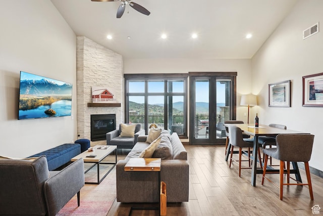 living area with wood finished floors, visible vents, a ceiling fan, and high vaulted ceiling