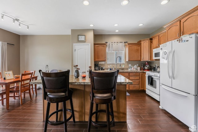 5454 N Windsor Way E, Stansbury Park, UT 84074 - kitchen with white appliances, wood finish floors, a center island, a kitchen breakfast bar, and recessed lighting