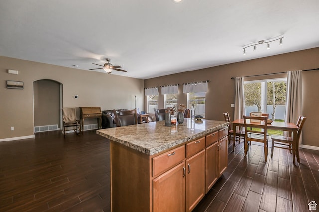 5454 N Windsor Way E, Stansbury Park, UT 84074 - kitchen featuring dark wood finished floors, a center island, ceiling fan, arched walkways, and brown cabinetry