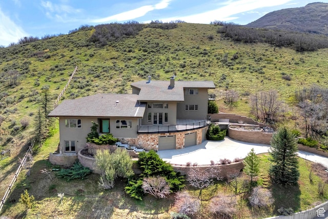 152 N Silver Oak Rd, Salt Lake City, UT 84108 - back of house featuring stucco siding, stone siding, a mountain view, concrete driveway, and an attached garage