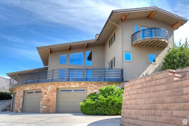 152 N Silver Oak Rd, Salt Lake City, UT 84108 - view of front of property with concrete driveway, stone siding, an attached garage, and a balcony