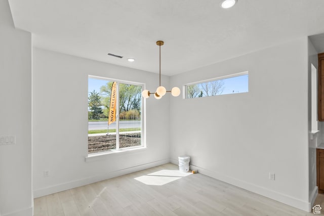 unfurnished dining area featuring a wealth of natural light, wood finished floors, and baseboards