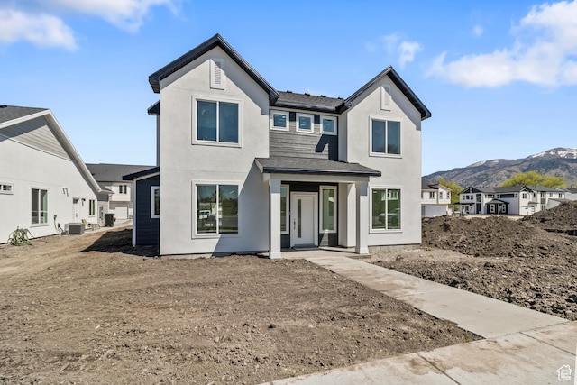 view of front facade with cooling unit, a mountain view, and stucco siding