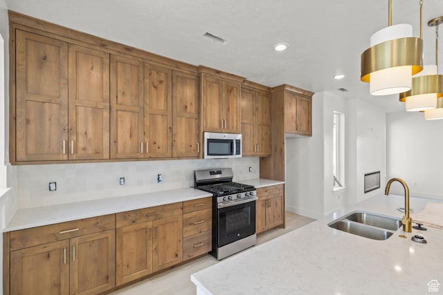 kitchen with appliances with stainless steel finishes, brown cabinets, decorative backsplash, and a sink