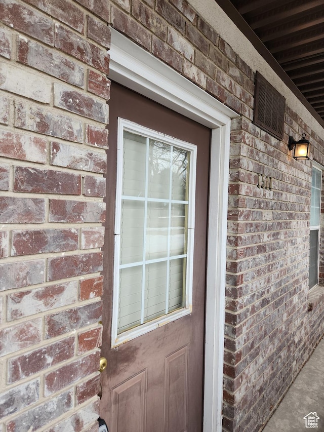 entrance to property featuring visible vents and brick siding