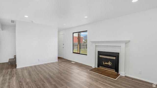 unfurnished living room featuring a fireplace with flush hearth, wood finished floors, recessed lighting, and visible vents