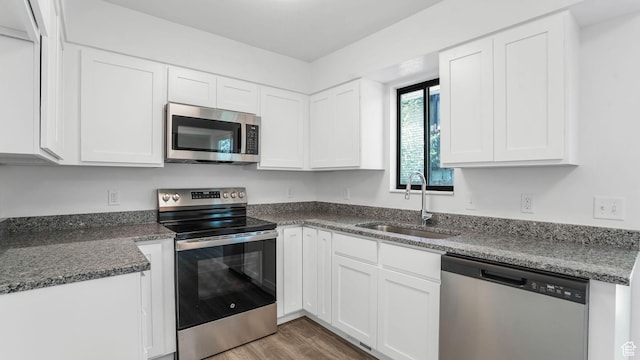 kitchen featuring stainless steel appliances, light wood-type flooring, white cabinets, and a sink