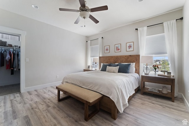 6463 W Maple Valley Cir S Unit 1030, West Jordan, UT 84081 - bedroom featuring a walk in closet, baseboards, a ceiling fan, and light wood-style flooring