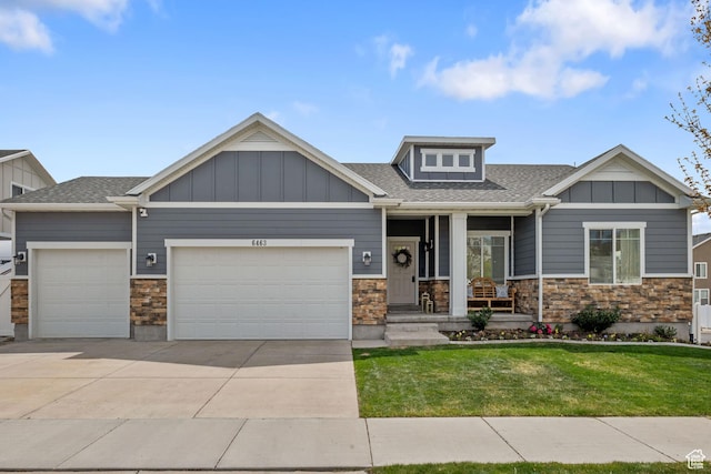 craftsman house with a front lawn, a garage, covered porch, driveway, and stone siding