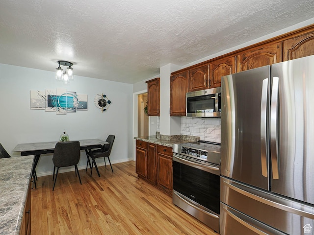 123 Lynnwood Dr, Clearfield, UT 84015 - kitchen with tasteful backsplash, light wood-style flooring, light stone counters, appliances with stainless steel finishes, and a textured ceiling