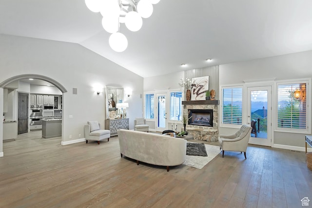 11274 S Eagle View Dr, Sandy, UT 84092 - living area with light wood-type flooring, a stone fireplace, vaulted ceiling, baseboards, and arched walkways