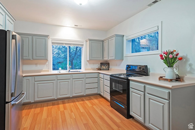 11274 S Eagle View Dr, Sandy, UT 84092 - kitchen with visible vents, freestanding refrigerator, a sink, light wood-type flooring, and black range with electric cooktop