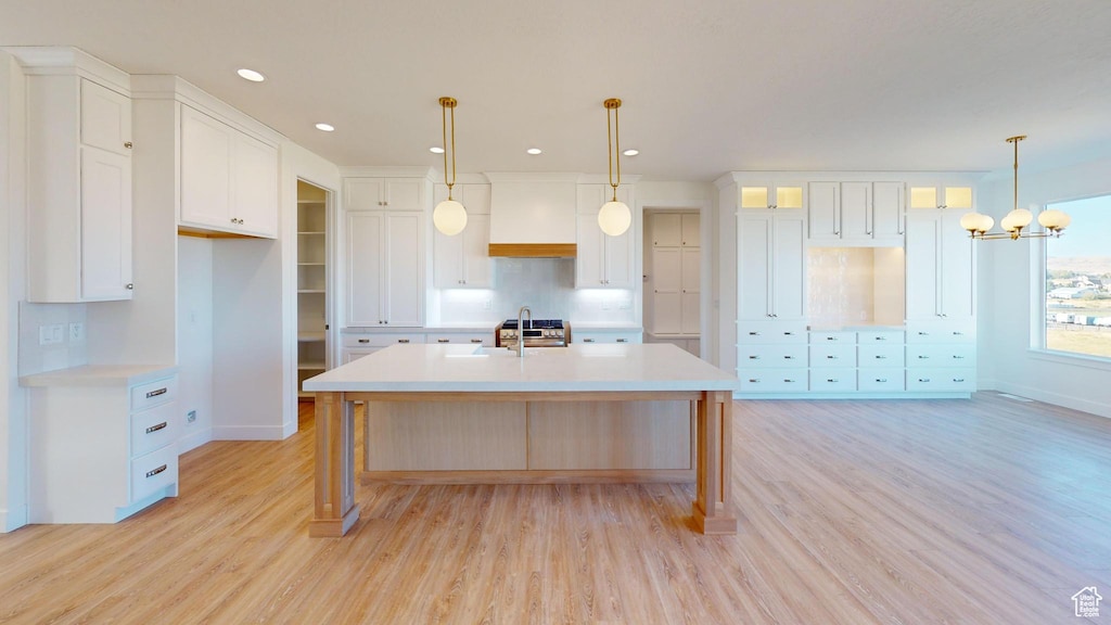 283 E 1250 N Unit 64, Salem, UT 84653 - kitchen with an island with sink, light wood-style flooring, light countertops, white cabinets, and premium range hood