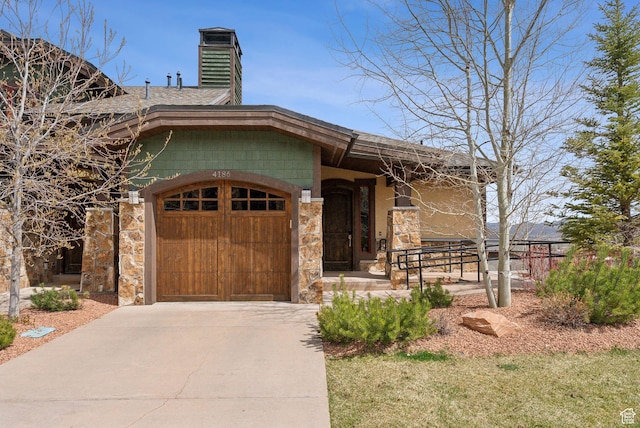 single story home featuring a chimney, a garage, driveway, and stone siding