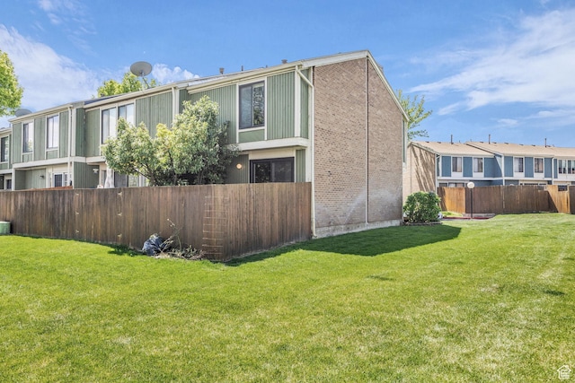 4169 S Village Ln Unit A, Taylorsville, UT 84129 - view of side of home with a lawn, fence private yard, and brick siding