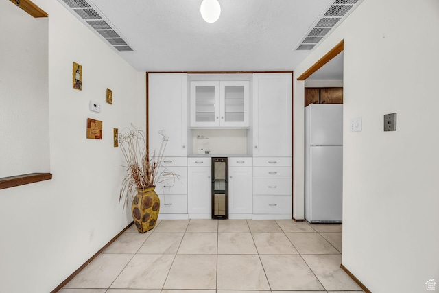 4169 S Village Ln Unit A, Taylorsville, UT 84129 - kitchen featuring glass insert cabinets, light tile patterned floors, visible vents, white cabinets, and freestanding refrigerator