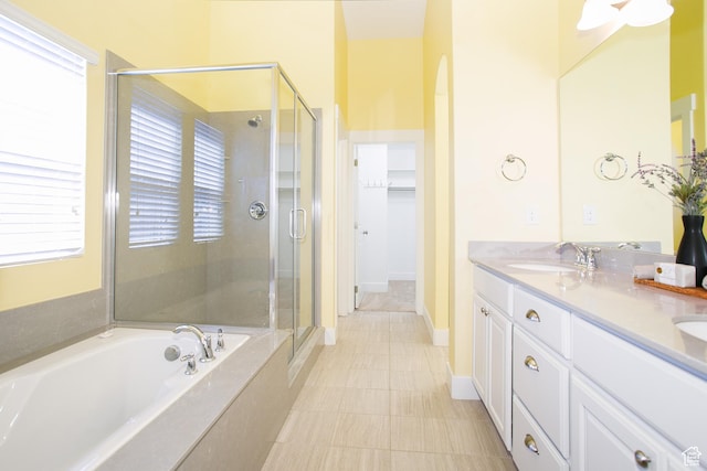 bathroom featuring a shower stall, a garden tub, double vanity, a walk in closet, and tile patterned floors