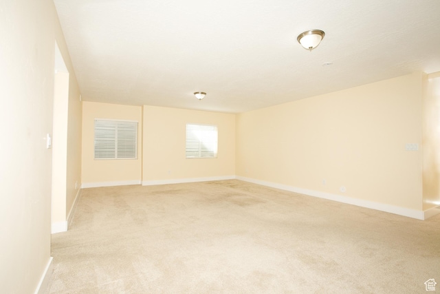 spare room with light carpet and baseboards