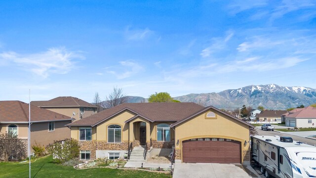 680 N 980 W, Tremonton, UT 84337 - view of front facade featuring driveway, stone siding, a mountain view, an attached garage, and stucco siding