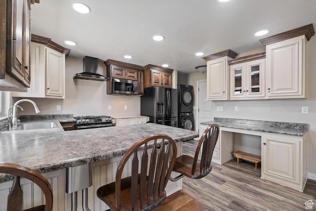 680 N 980 W, Tremonton, UT 84337 - kitchen with stacked washer and dryer, a sink, stainless steel appliances, wall chimney exhaust hood, and a peninsula