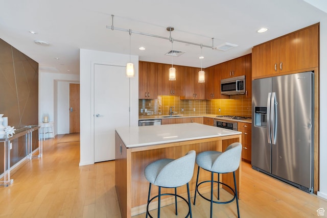 35 E 100 S Unit 1504, Salt Lake City, UT 84111 - kitchen featuring a breakfast bar area, appliances with stainless steel finishes, brown cabinets, light wood-type flooring, and visible vents