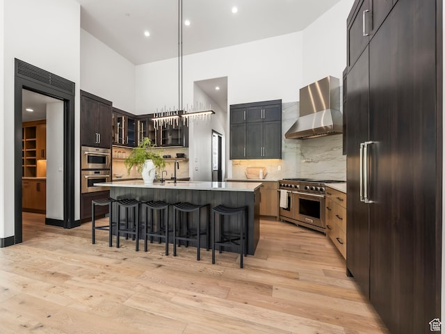897 S Summit Creek Dr, Woodland Hills, UT 84653 - kitchen with wall chimney range hood, a kitchen breakfast bar, decorative backsplash, premium appliances, and a towering ceiling