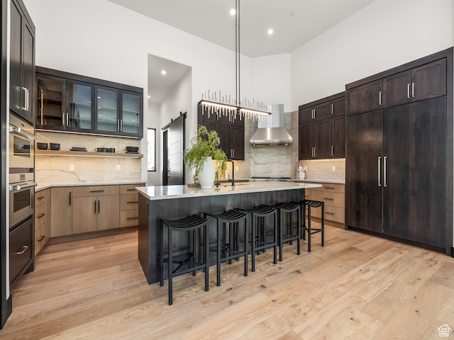 897 S Summit Creek Dr, Woodland Hills, UT 84653 - kitchen with a kitchen bar, backsplash, wall chimney exhaust hood, and light wood finished floors