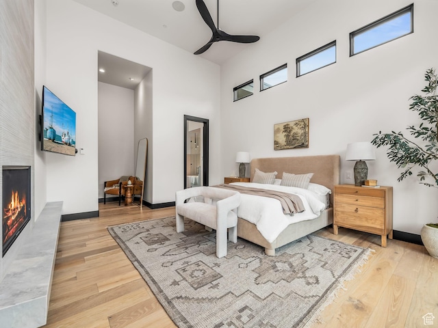 897 S Summit Creek Dr, Woodland Hills, UT 84653 - bedroom featuring a fireplace, a towering ceiling, light wood finished floors, and baseboards