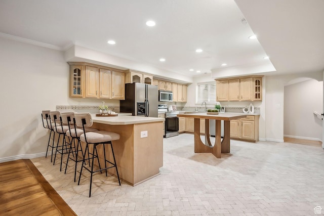 kitchen featuring a breakfast bar area, glass insert cabinets, stainless steel appliances, light countertops, and a peninsula