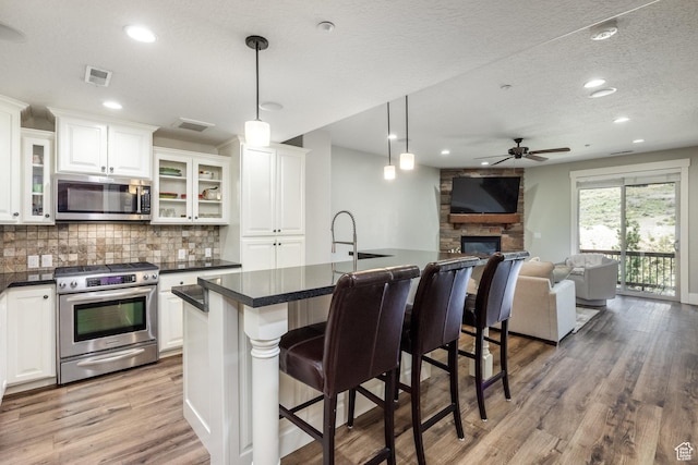 13386 N Alexis Dr, Kamas, UT 84036 - kitchen featuring stainless steel appliances, ceiling fan, decorative backsplash, dark countertops, and a kitchen breakfast bar