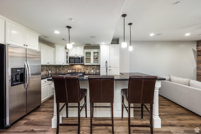 13386 N Alexis Dr, Kamas, UT 84036 - kitchen with appliances with stainless steel finishes, dark countertops, white cabinetry, tasteful backsplash, and a kitchen breakfast bar