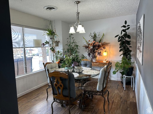 dining space featuring baseboards, visible vents, wood finished floors, and a textured ceiling