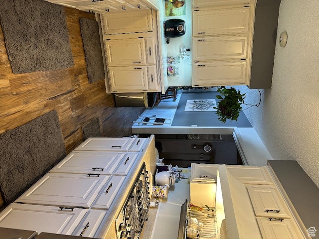 kitchen featuring white cabinets, wood finished floors, and a textured wall