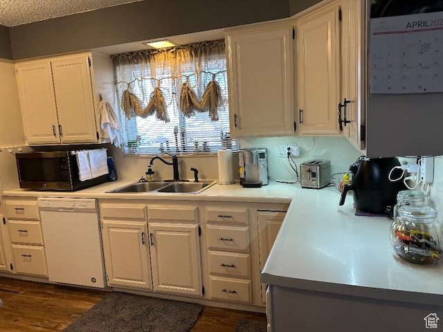 kitchen with stainless steel microwave, white cabinets, a sink, light countertops, and dishwasher